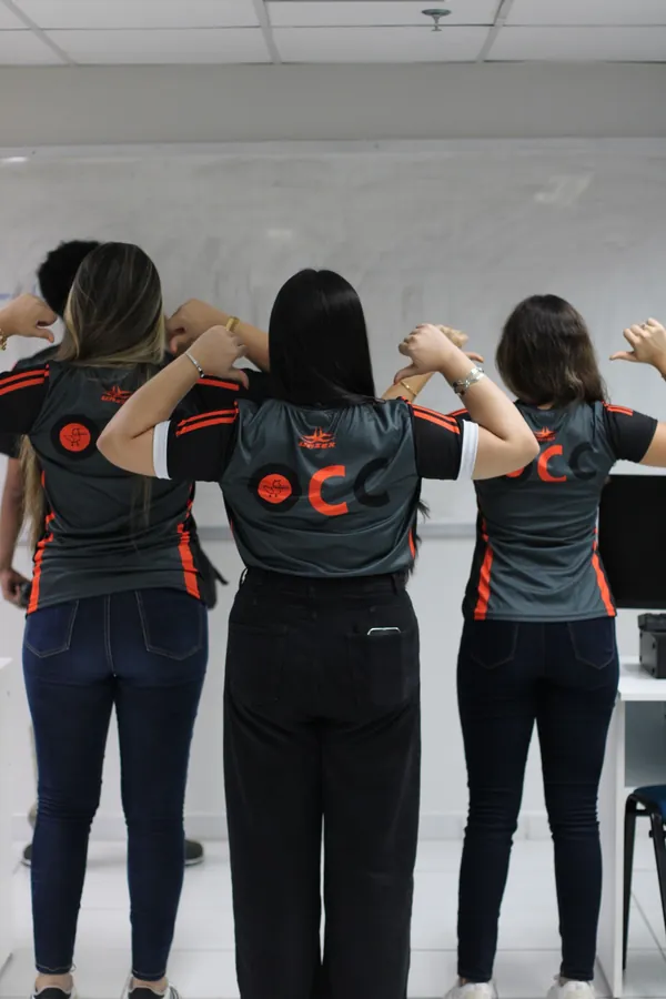 Três participantes de costas mostrando as camisas do evento