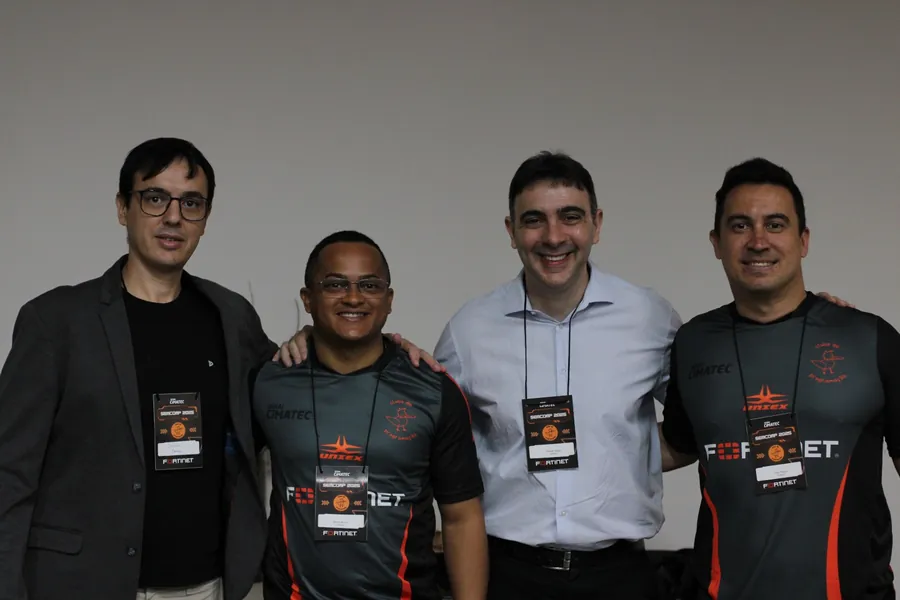 Quatro pessoas posando, duas com a camisa da Fortinet