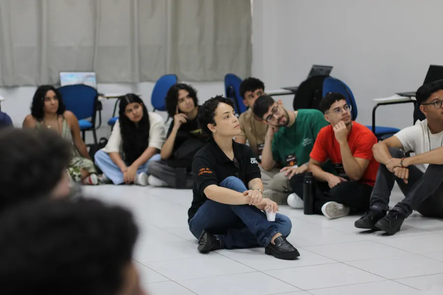 Participantes sentados no chão de uma sala, em roda