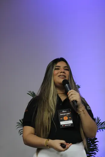 Palestrante com microfone na mão, diante do telão