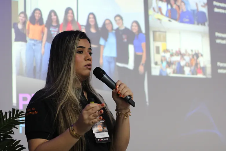 Palestrante falando ao microfone em frente à projeção