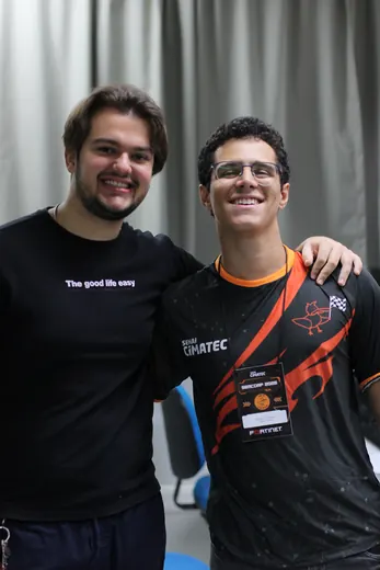 Dois participantes abraçados, um com a camisa do clube