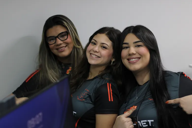 Três participantes sorrindo com as camisas do evento